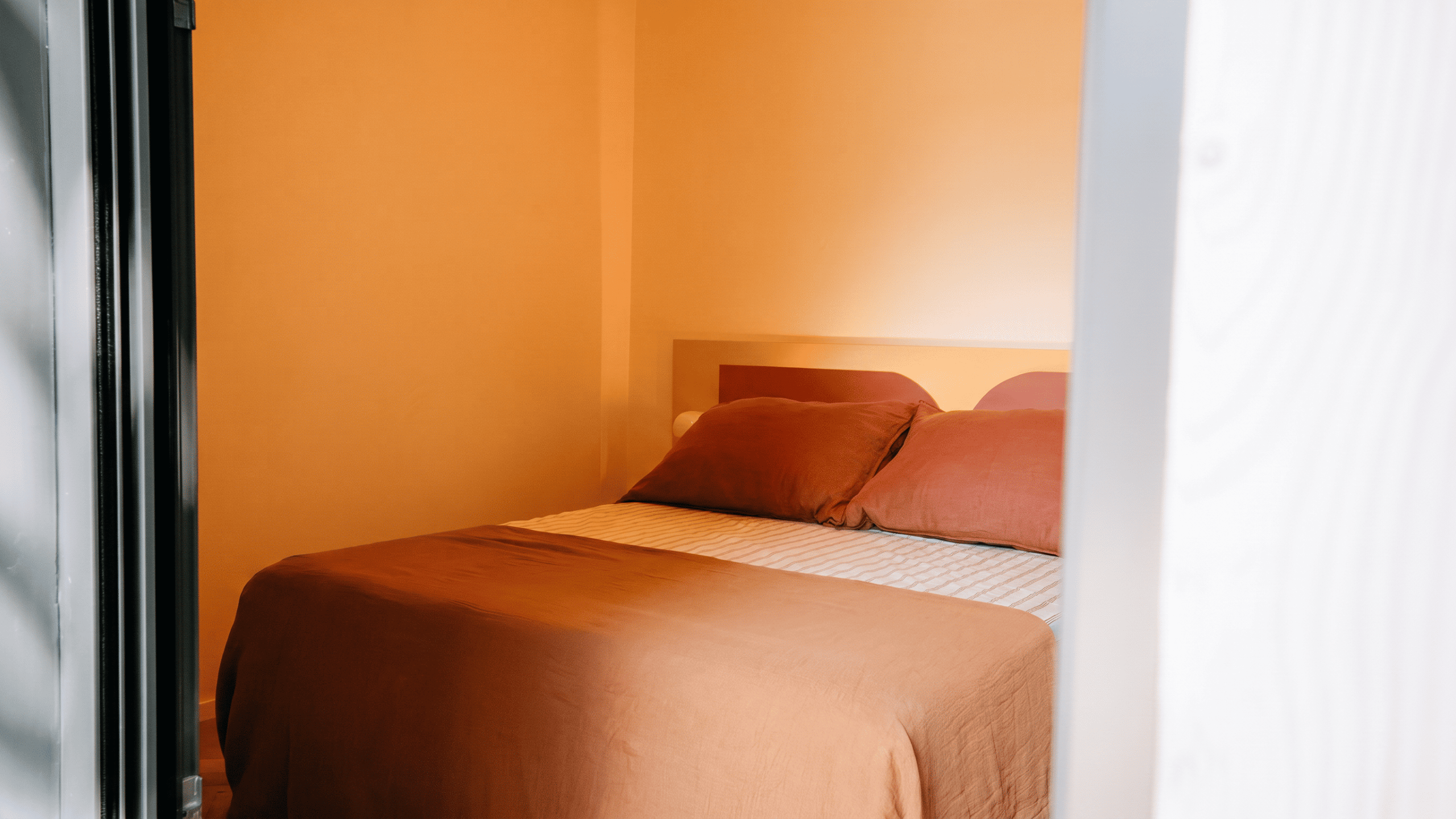 Chambre à coucher avec mur et parure de lit de couleur terracotta dans une maison d'architecte à Vannes.
