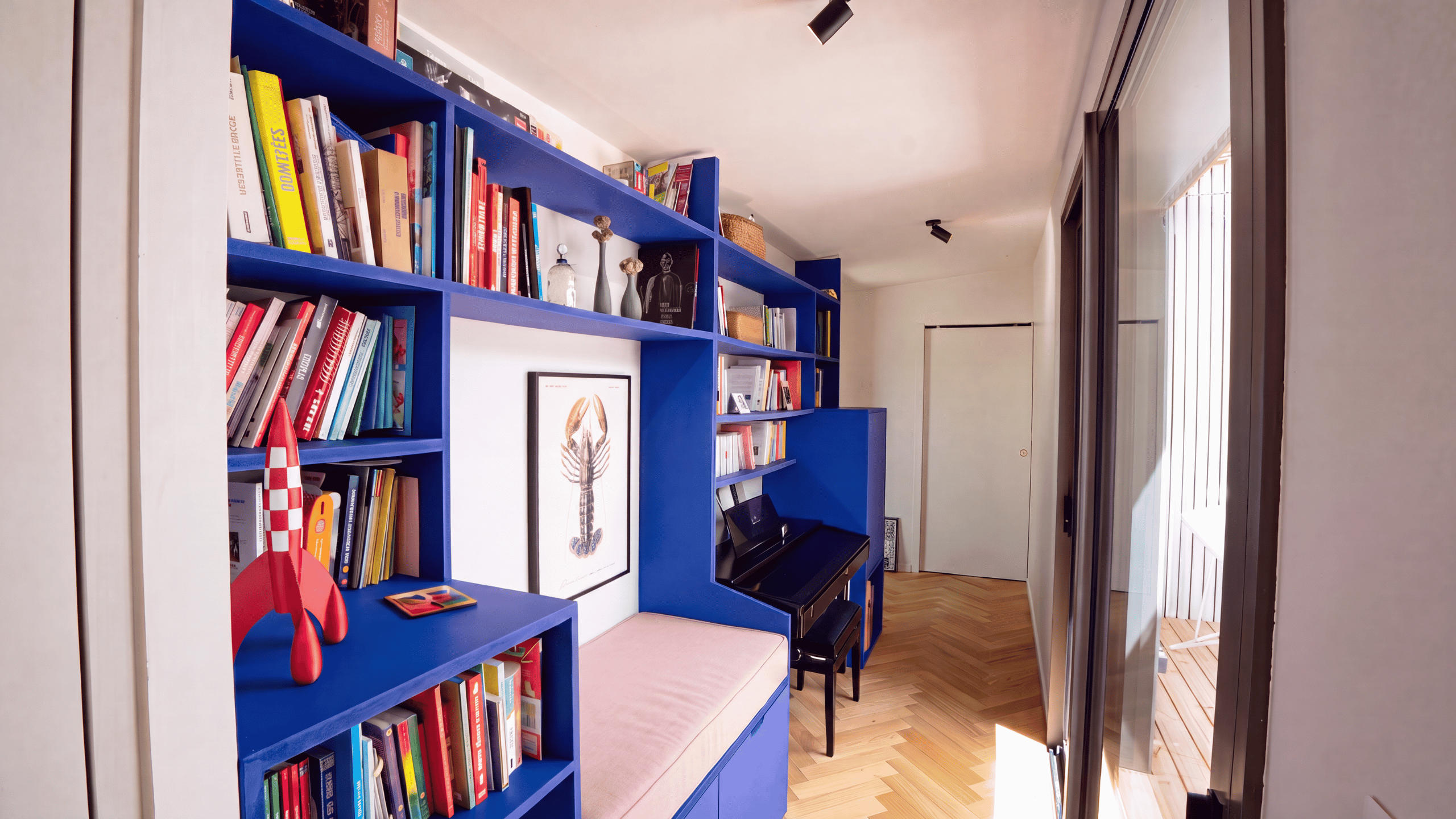 Bibliothèque sur mesure en bois bleu avec bureau et banquette intégrés dans une maison d'architecte à Vannes.