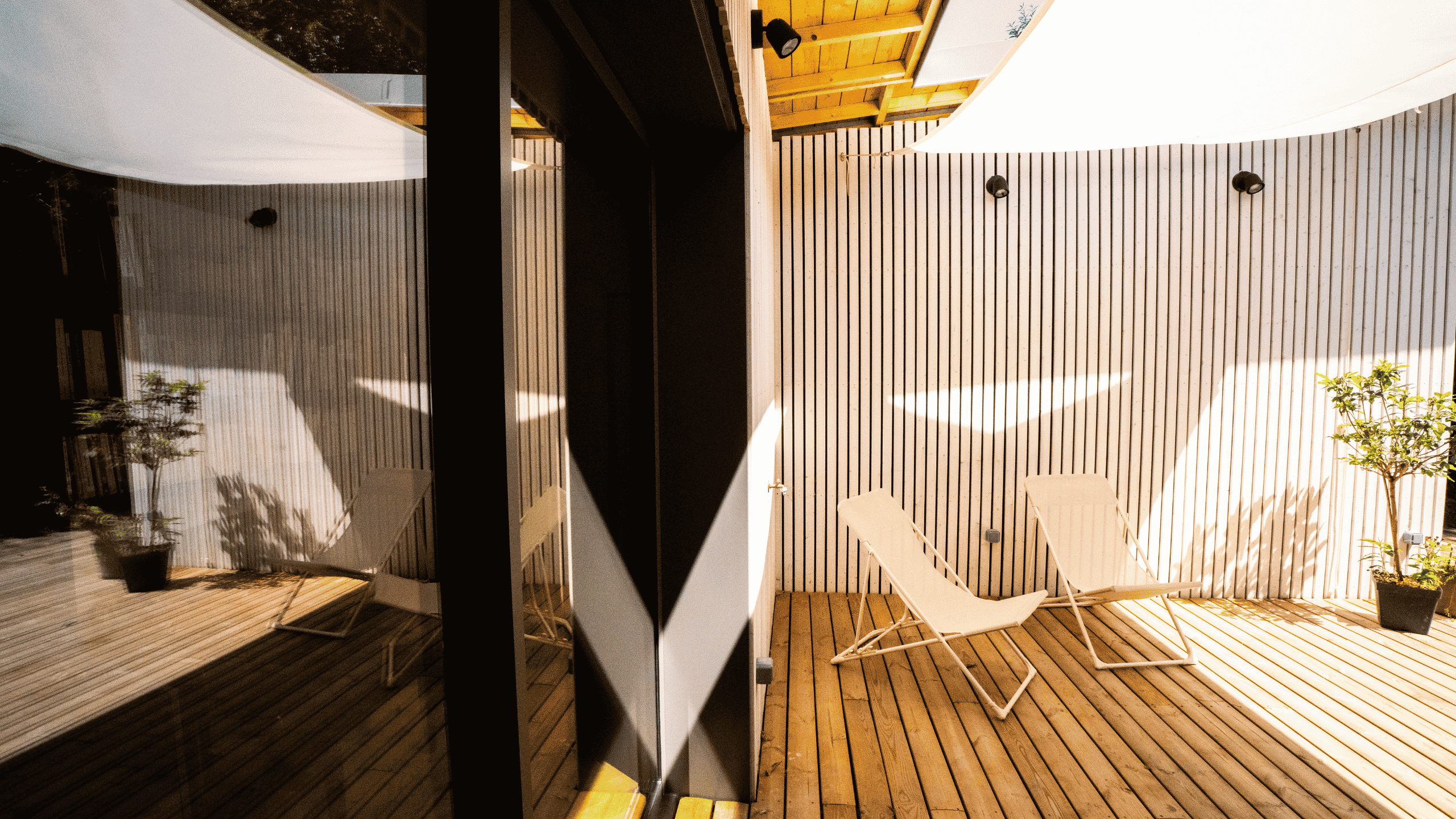 Terrasse en bois avec chiliennes, voile d'ombrage et baies vitrées dans une maison d'architecte à Vannes.